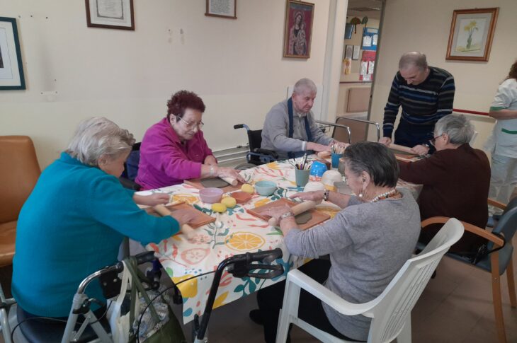 Anziani riuniti intorno a un tavolo, impegnati nella lavorazione della ceramica